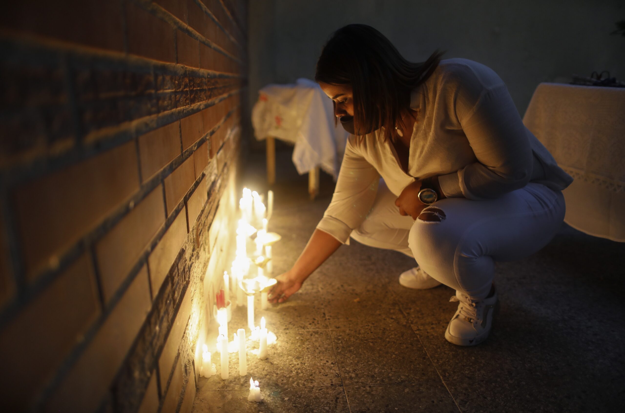 Grey Zapata places a lit candle in Caracas, Venezuela, Wednesday, Dec. 16, 2020, during a vigil for victims found drowned this past weekend. Two boats carrying some 40 Venezuelan migrants disappeared nearly two weeks ago, headed to the nearby eastern Caribbean nation of Trinidad and Tobago to visit family members or to buy goods not available in Venezuela given the scarcity of food in their country, according to a resident of Güiria who asked that her name be withheld for fear of reprisal from authorities. (AP Photo/Ariana Cubillos)